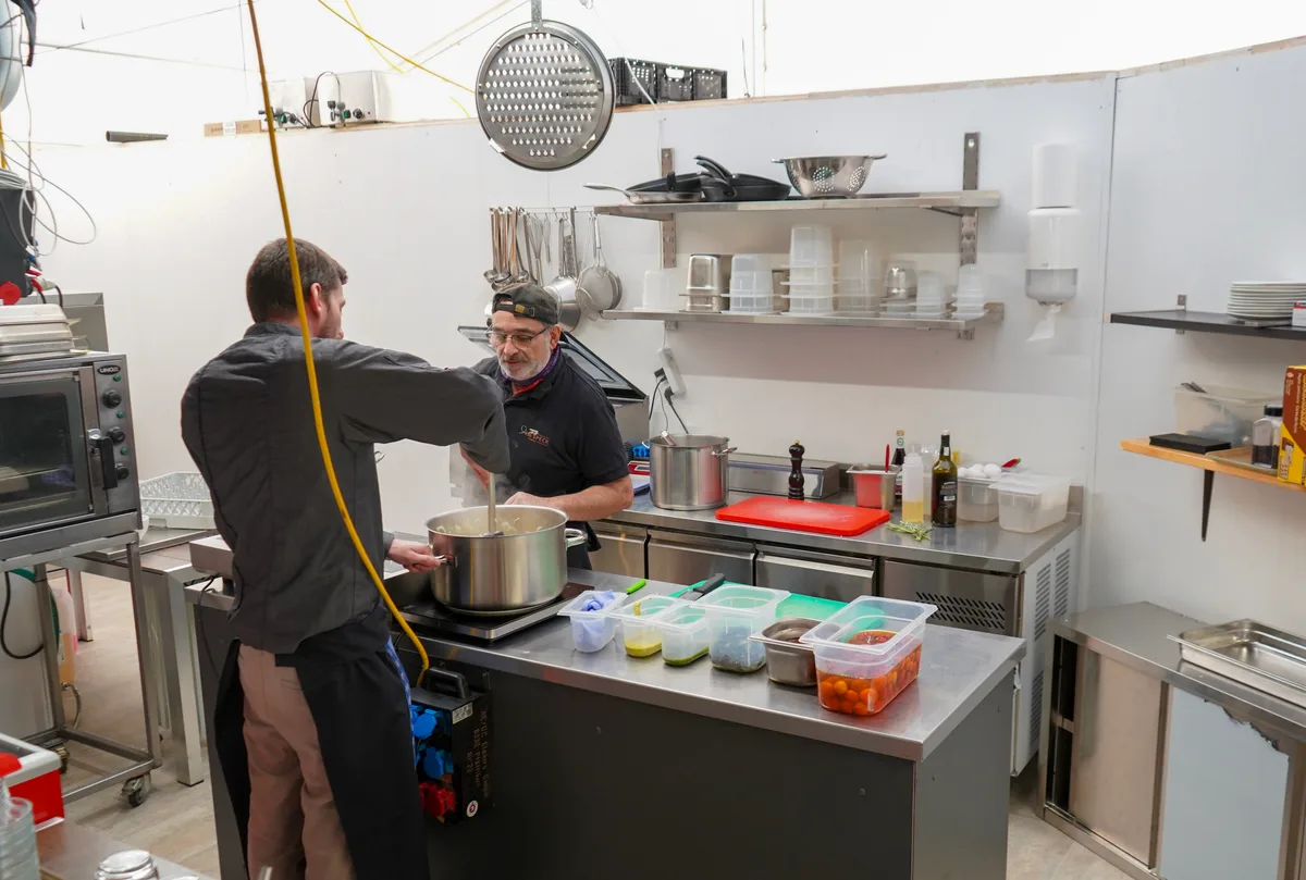 Man sieht eine Gastronomieküche und zwei Kochende.